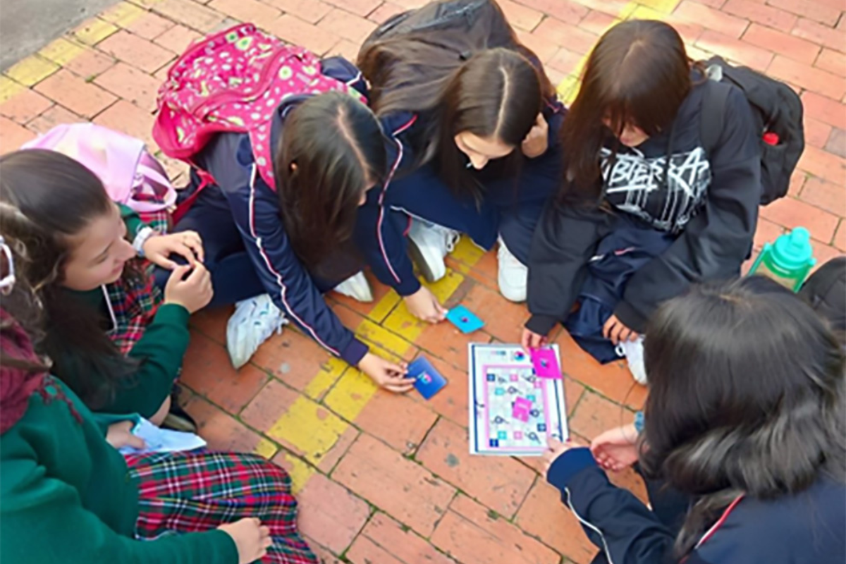 6 niñas sentadas en el suelo en forma de circulo realizando una actividad 