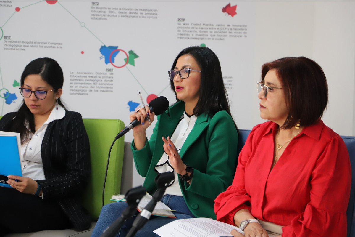 Foto de la profe Natalia Pinilla junto a otras dos profes en un panel