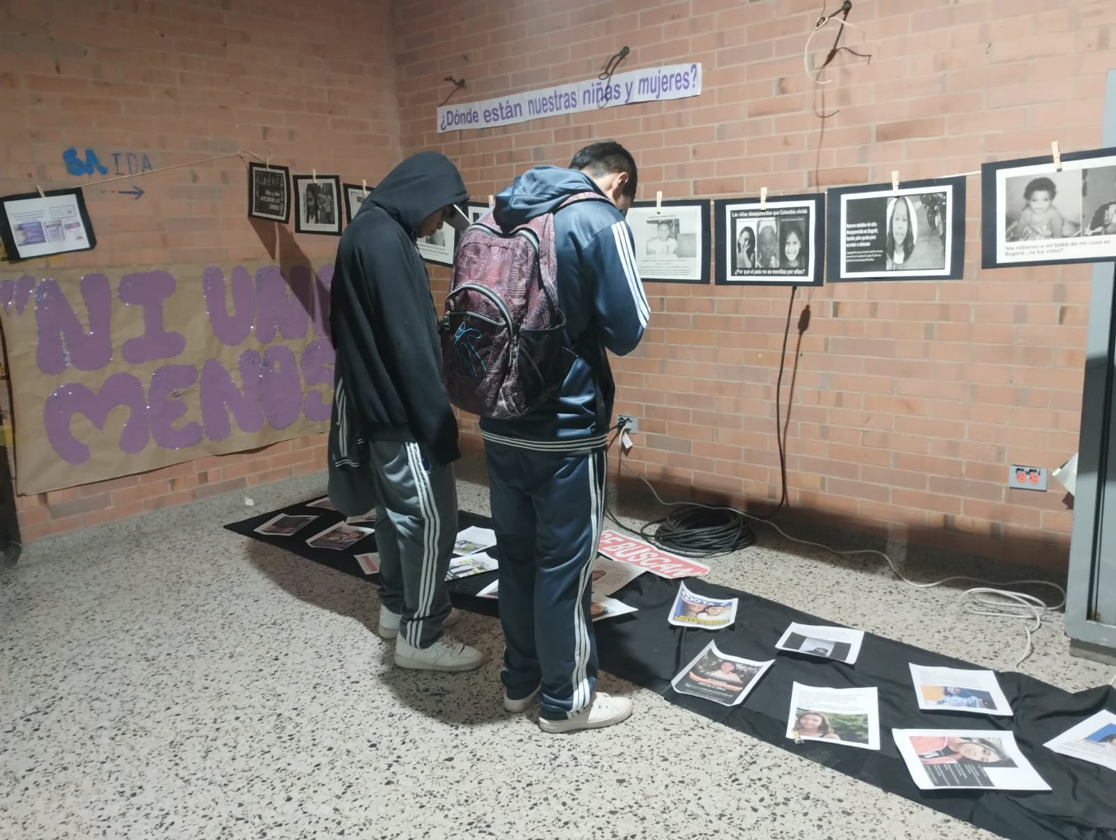 Estudiantes viendo unas fotografías que están en el suelo