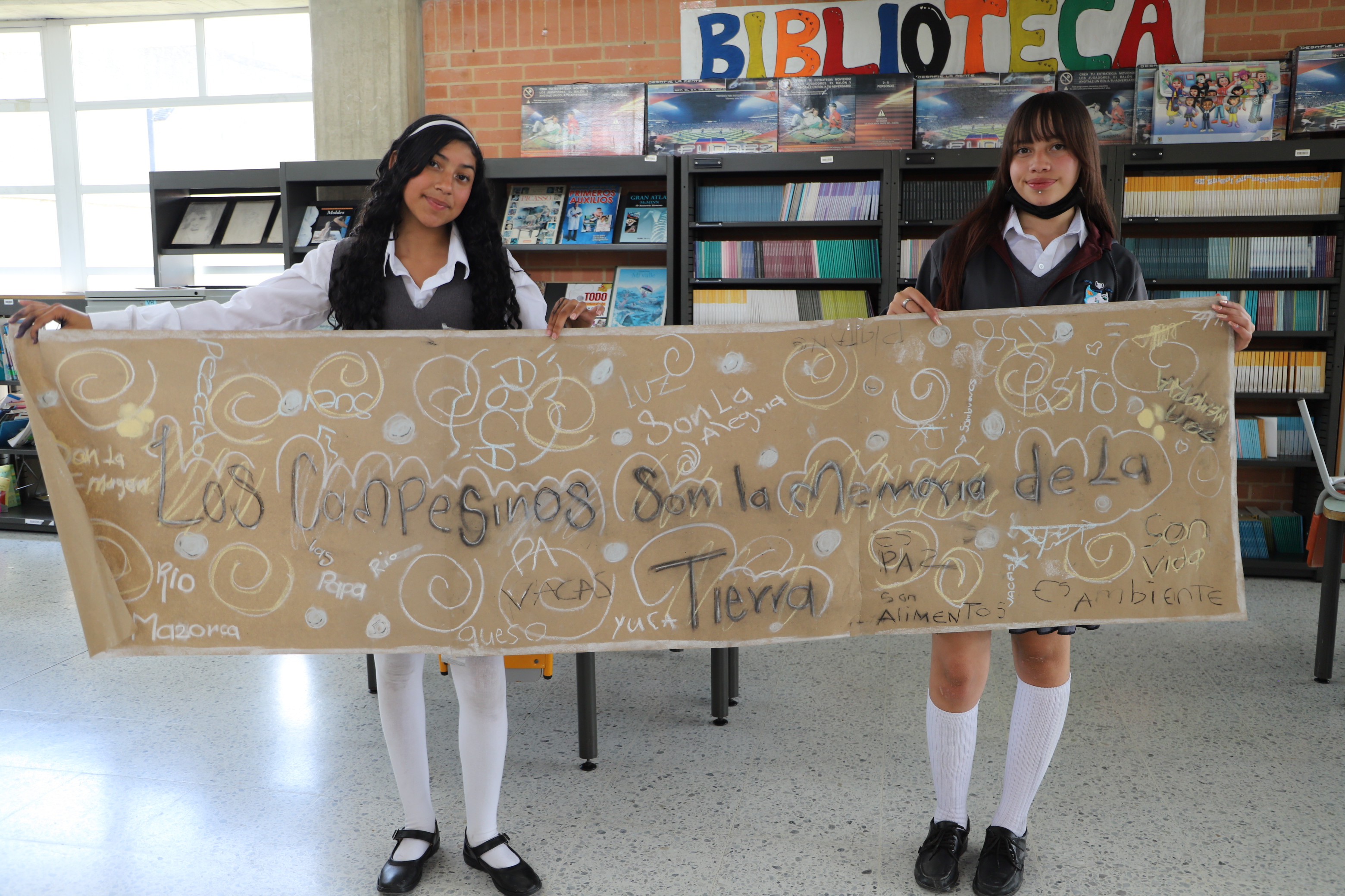 Dos estudiantes mostrando una pancarta: Los campesinos son la memoria de la tierra