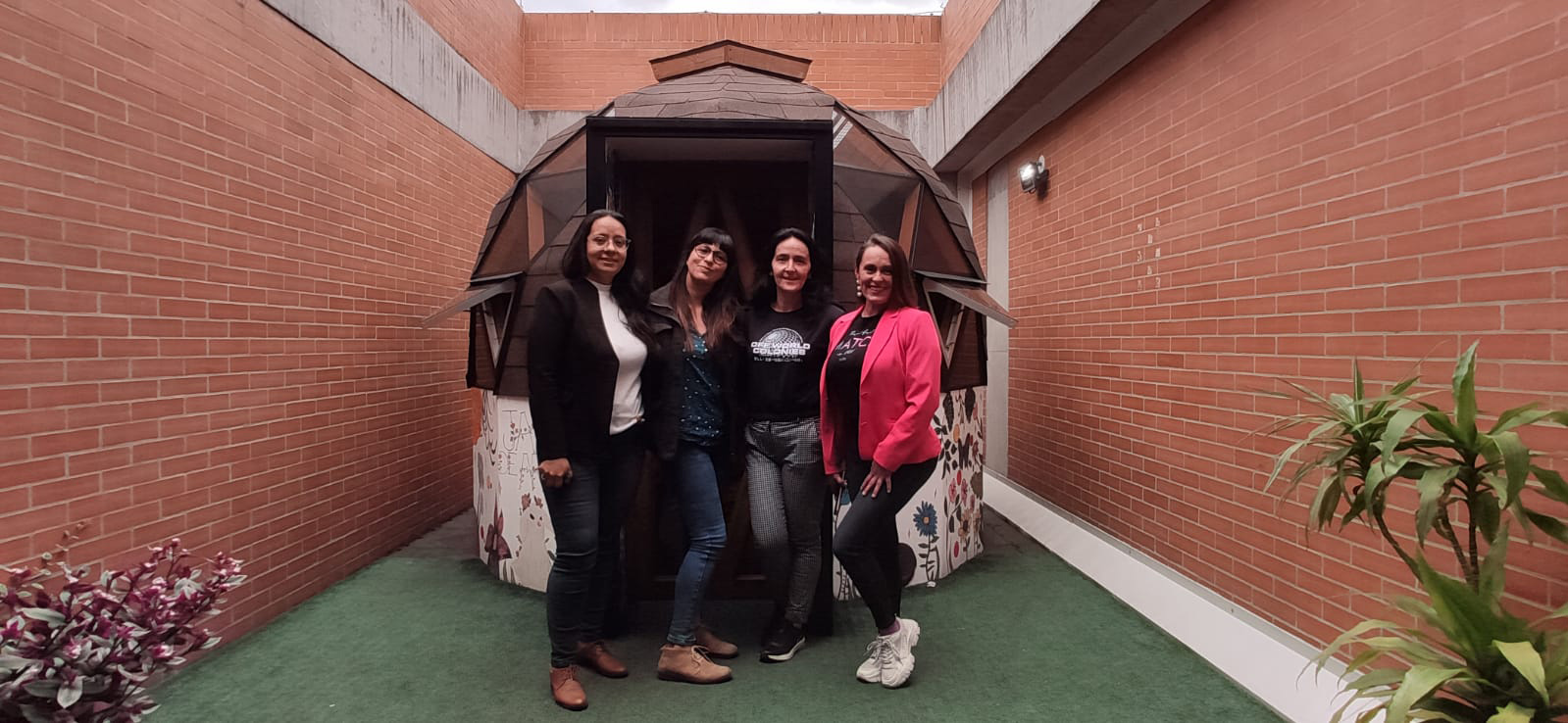 Foto de cuatro profesoras junto al domo de madera