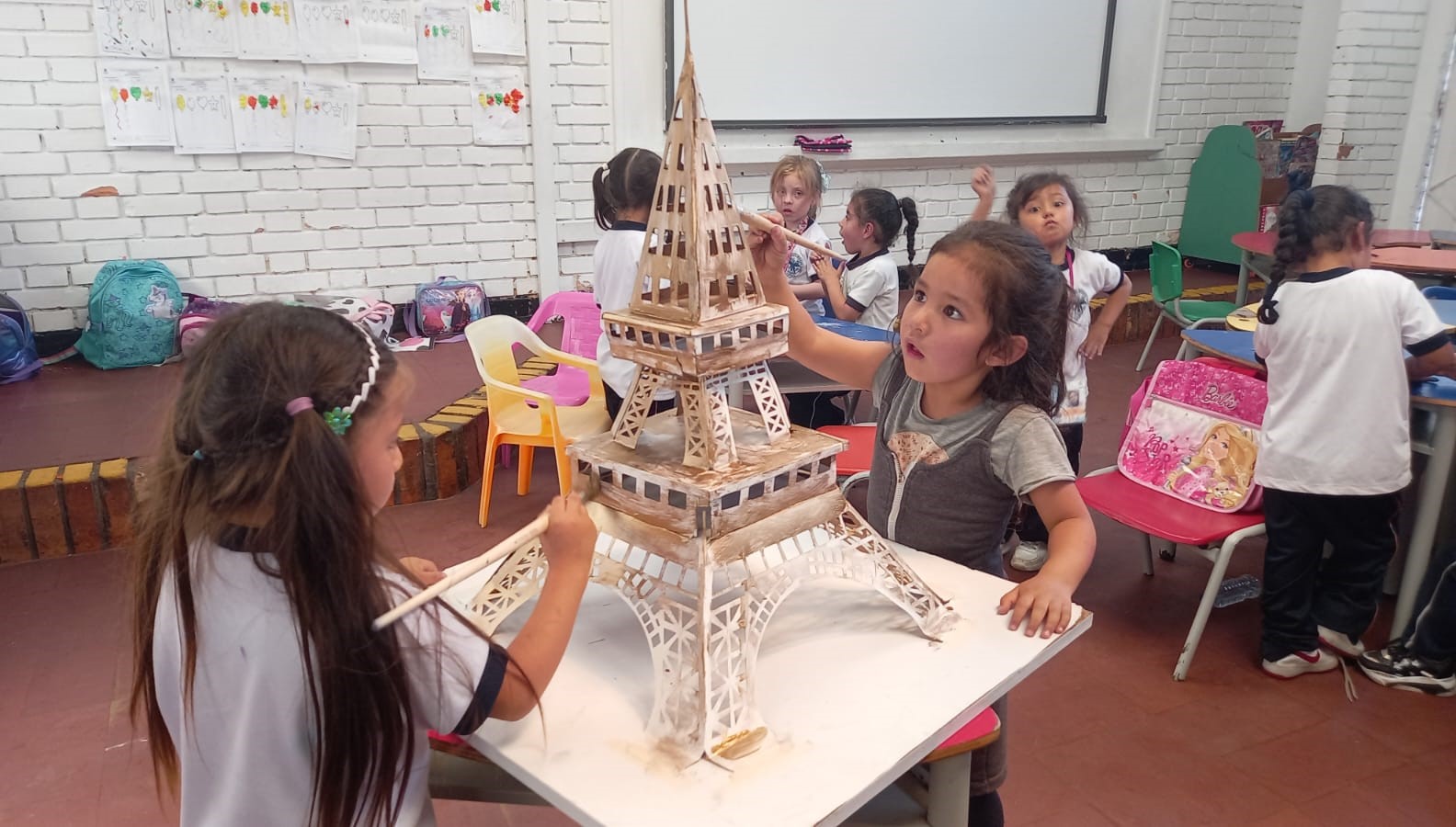 Foto de dos niñas pintando una torre eiffel 