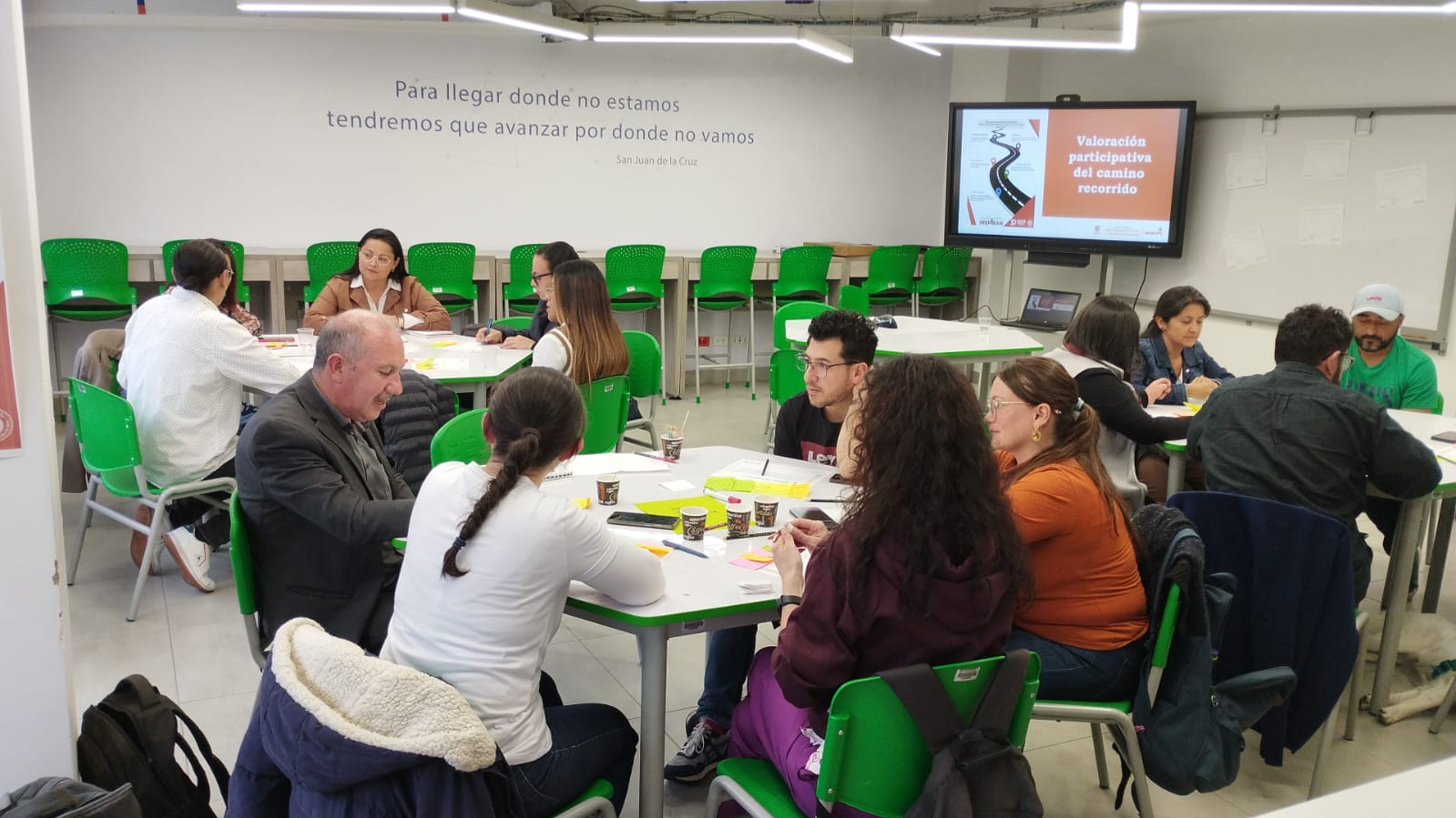 Maestros y maestras sentados en mesas por grupos