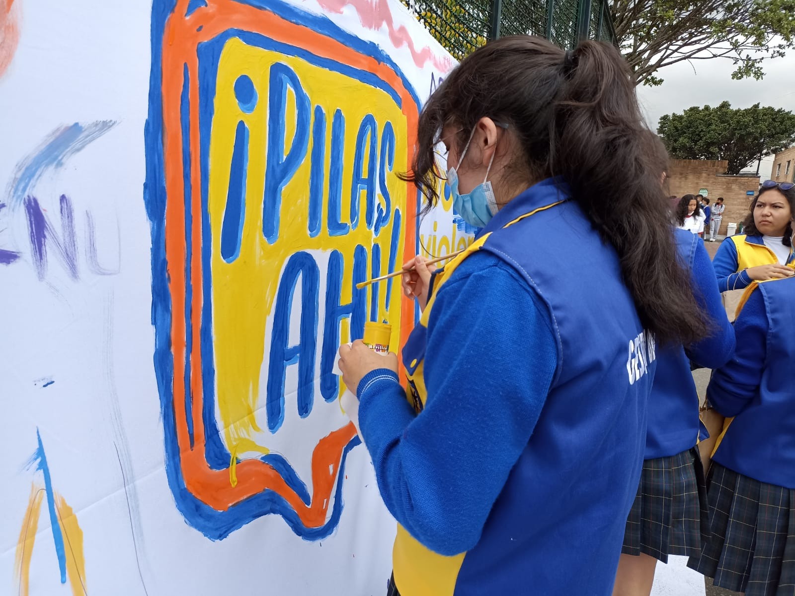 Una niña pintando en al pared "Pilas ahí"